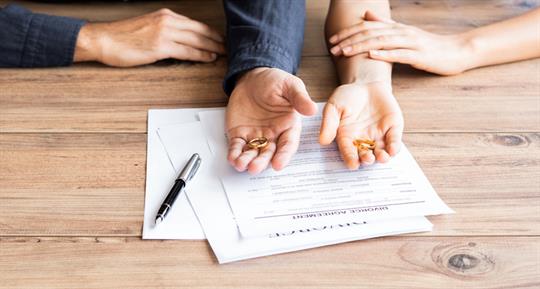 couple holding wedding rings before signing divorce agreement